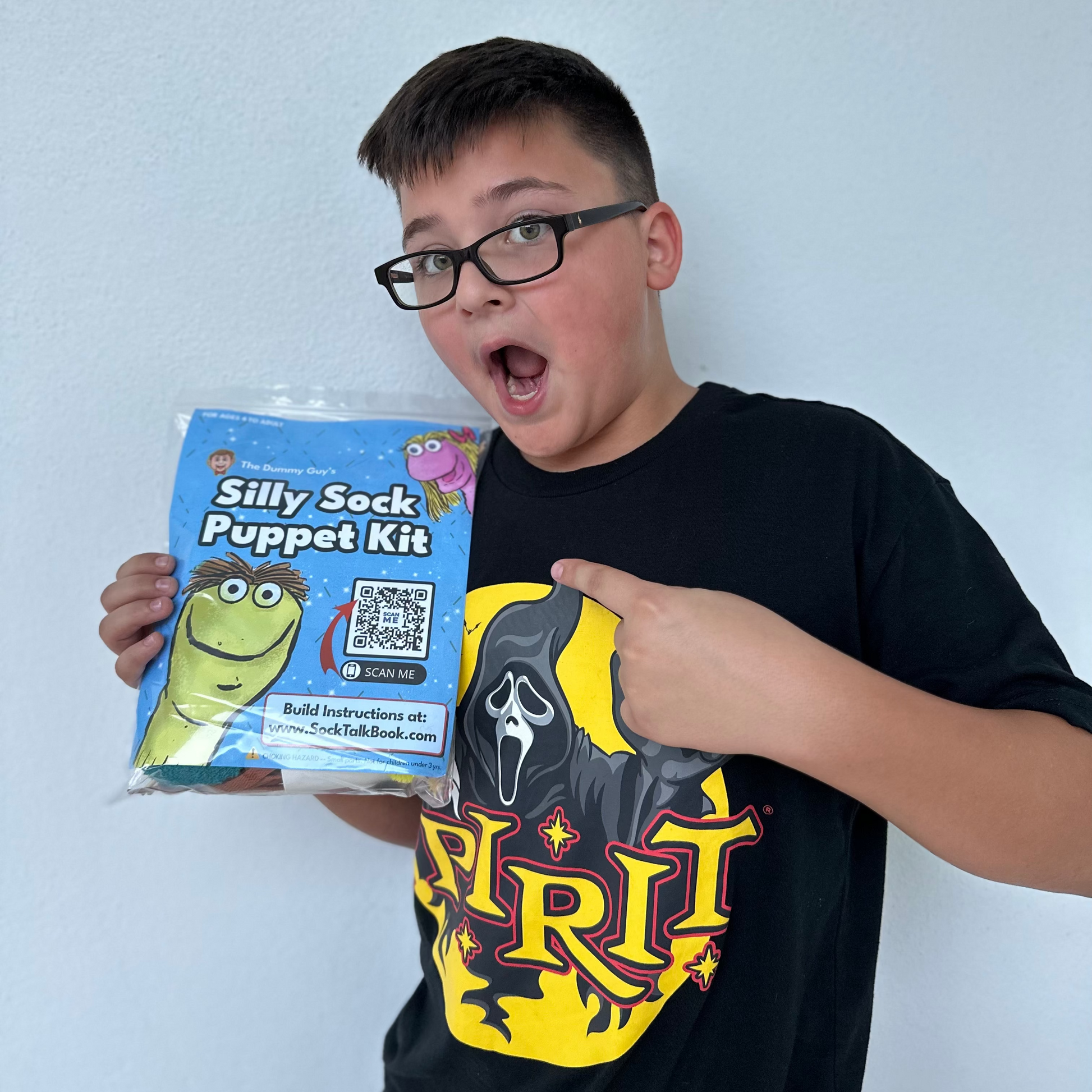 A boy holding The Dummy Guy's Silly Sock Puppet Kit, a sock puppet craft kit for kids learning ventriloquism.